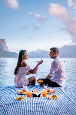 Khao Sok Tayland, Tayland 'daki Khao Sok Ulusal Parkı' nda yüzen bungalovun önünde kahvaltı yapan çift.