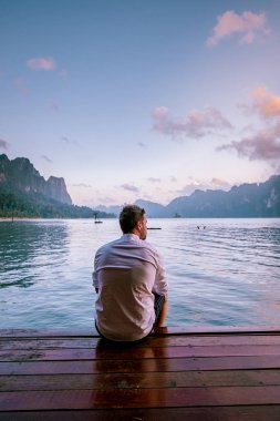 young men in front of floating bungalow during sunrise in national park Khao Sok Thailand