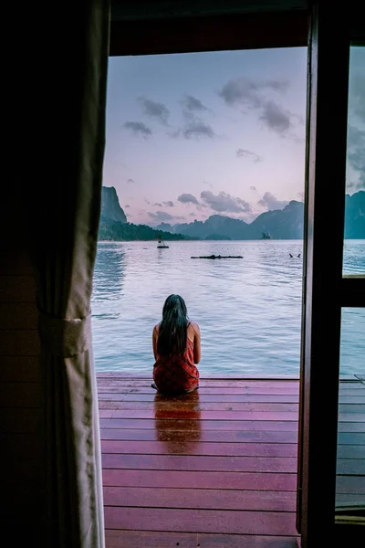 Woman watching sunrise in front of floating bungalow in Khao Sok Thailand — 스톡 사진