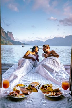 Khao Sok Tayland, Tayland 'daki Khao Sok Ulusal Parkı' nda yüzen bungalovun önünde kahvaltı yapan çift.