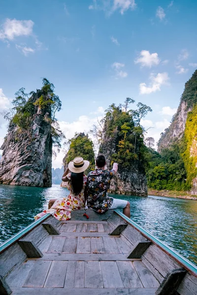 Pasangan bepergian dengan perahu menjelajahi tebing batu kapur epik di danau besar di Taman Nasional Khao Sok, danau Chiew lan, Thailand — Stok Foto