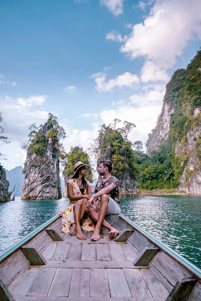 Pasangan bepergian dengan perahu menjelajahi tebing batu kapur epik di danau besar di Taman Nasional Khao Sok, danau Chiew lan, Thailand — Stok Foto