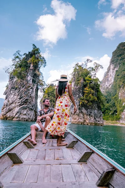 Par som reiser med båt og utforsker episke kalksteinsklipper i en stor innsjø i Khao Sok nasjonalpark, Chiew lan lake, Thailand – stockfoto