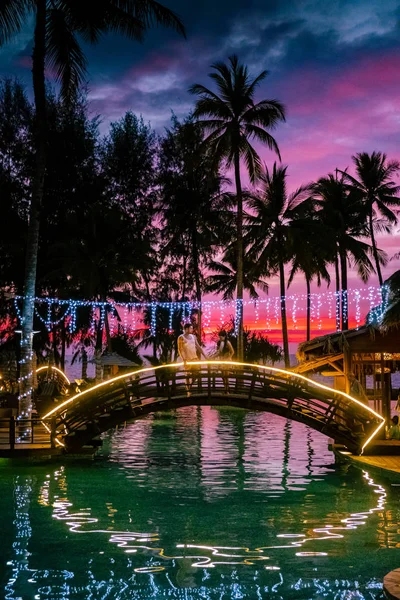 Çiftler kumsalda gün batımını ve Tayland 'da lüks bir tatil köyü olan Khao Lak' ın havuzunu izliyorlar. — Stok fotoğraf