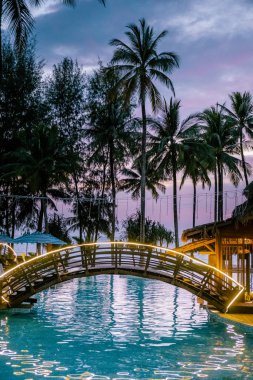 couple watching sunset by the beach and the pool of an luxury resort in Thailand Khao Lak clipart