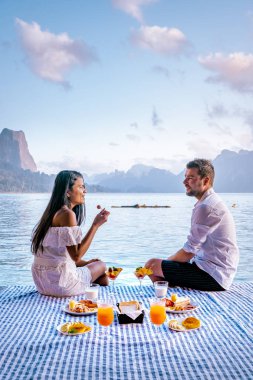 Khao Sok Tayland, Tayland 'daki Khao Sok Ulusal Parkı' nda yüzen bungalovun önünde kahvaltı yapan çift.
