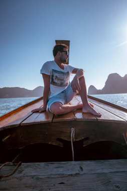young men traveling in longtail boat, Phangnga Bay Thailand ocean, famous for its many Islands and lagoon in the ocean
