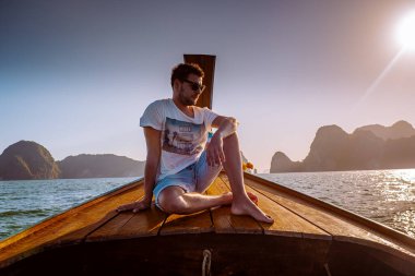 young men traveling in longtail boat, Phangnga Bay Thailand ocean, famous for its many Islands and lagoon in the ocean