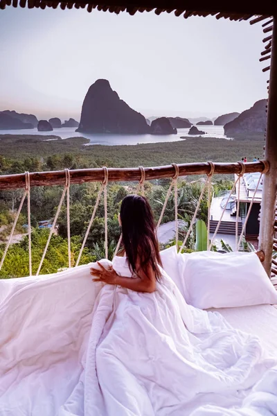 Женщина в спальне просыпаясь утром, глядя на залив Phangnga Таиланд во время восхода солнца Таиланд роскошные каникулы в природе — стоковое фото