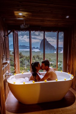 couple on honeymoon vacation, Bath tub with a look over the bay of Phangnga bay, Luxury wooden bathroom during sunset Thailand Asia