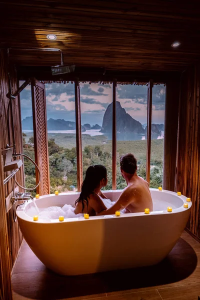 Casal em férias de lua de mel, banheira com um olhar sobre a baía de Phangnga, banheiro de madeira de luxo durante o pôr do sol Tailândia Ásia — Fotografia de Stock