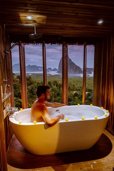 Young men in Bath tub with a look over the bay of Phangnga bay, Luxury wooden bathroom during sunset Thailand Asia — Stok fotoğraf