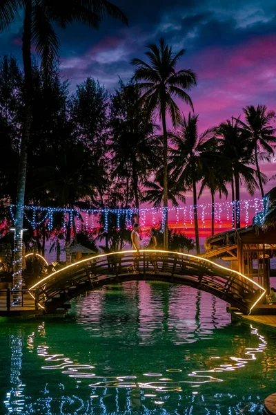 Çiftler kumsalda gün batımını ve Tayland 'da lüks bir tatil köyü olan Khao Lak' ın havuzunu izliyorlar. — Stok fotoğraf