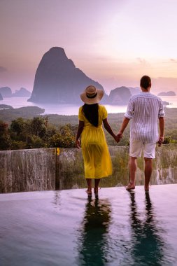 Phangnga Bay Thailand, couple on the edge of an swimming pool watching sunrise Thailand infinity pool