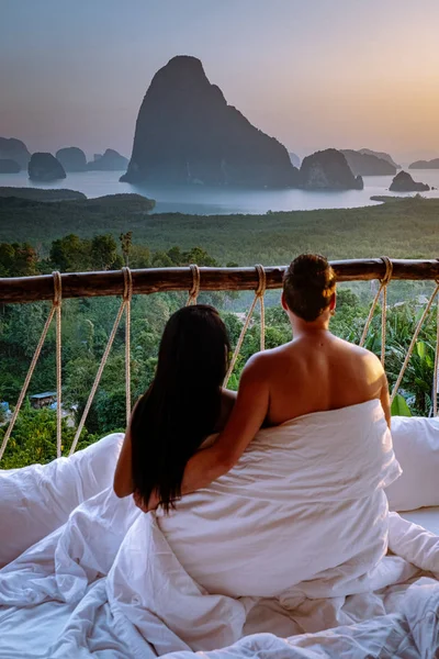 Pár felébred az ágyban a természet dzsungelben néz ki az óceán felett napkeltekor fa kunyhó a hegyekben Thaiföld — Stock Fotó