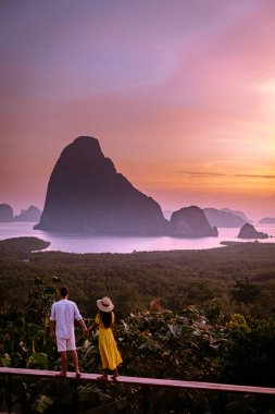 couple watching sunrise over the bay of Phangnga Thailand, men and woman at Samet Nang She viewpoint during sunrise Thailand