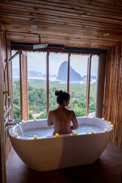 Vrouw kijken zonsondergang in bad in de badkamer tijdens vakantie in Thailand kijken zonsondergang over de oceaan en moutnains — Stockfoto