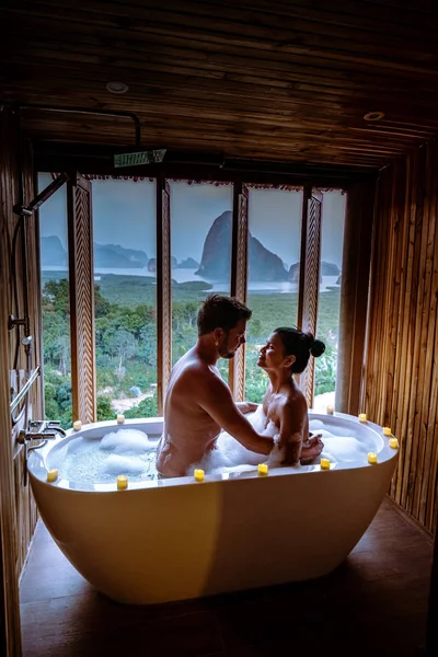 Couple watching sunset in bathtub in the bathroom during vacation in Thailand watching sunset over the ocean and moutnains — 图库照片