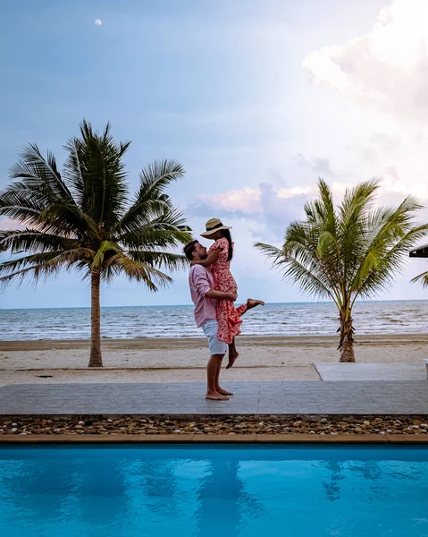 Pareja en la playa con palmera y piscina en Tailandia Zona de Chumphon durante el atardecer en la playa de Arunothai —  Fotos de Stock