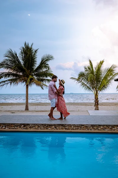 Couple on the beach with palm tree and swimming pool in Thailand Chumphon area during sunset at Arunothai beach — Stock Photo, Image