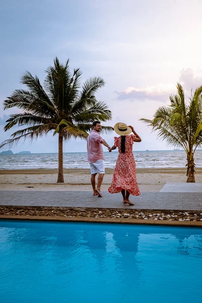 Paar op het strand met palmboom en zwembad in Thailand Chumphon gebied tijdens zonsondergang op Arunothai strand — Stockfoto