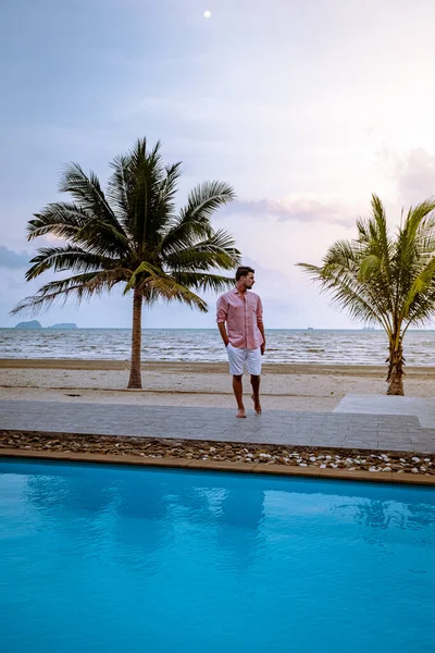 Men on the beach with palm tree and swimming pool in Thailand Chumphon area during sunset at Arunothai beach — Stok fotoğraf