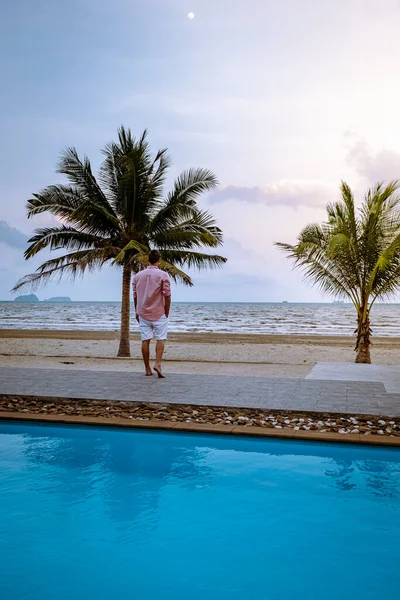 Homens na praia com palmeira e piscina na Tailândia Chumphon área durante o pôr do sol na praia de Arunothai — Fotografia de Stock