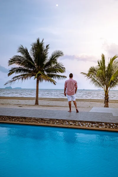 Men on the beach with palm tree and swimming pool in Thailand Chumphon area during sunset at Arunothai beach — Stok fotoğraf