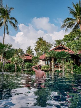 guy on the beach with palm tree and swimming pool in Thailand Chumphon area during sunset at Arunothai beach