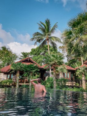 guy on the beach with palm tree and swimming pool in Thailand Chumphon area during sunset at Arunothai beach