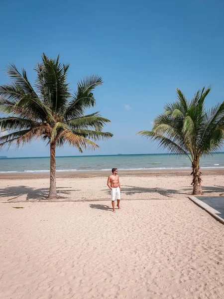 Guy on the beach with palm tree and swimming pool in Thailand Chumphon area during sunset at Arunothai beach — 스톡 사진