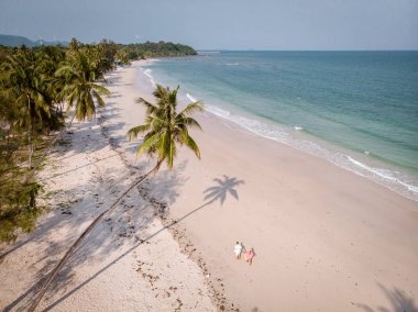 Tayland 'ın Chumphon bölgesindeki Thun Wua Laen plajı, yukarıdan beyaz kumlu ve palmiye ağaçlı İHA manzarası, beyaz sahilde yürüyen çift.