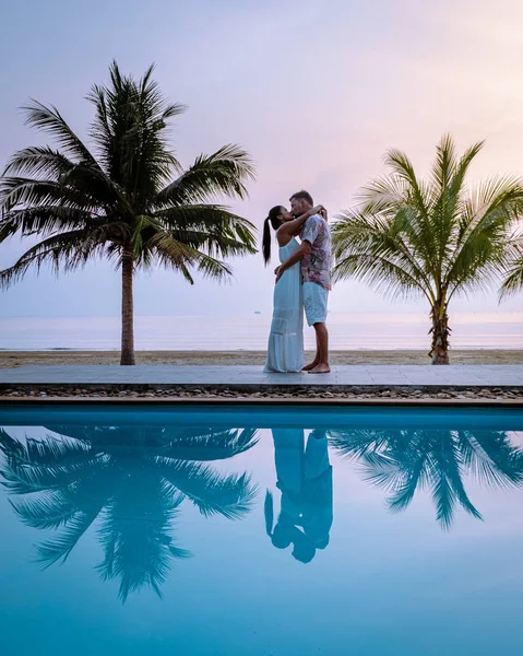 Couple men and woman during sunrise by the swimming pool looking out over the beach of Chumphon Thailand — 스톡 사진