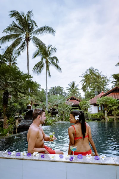 Casal bebendo coquetéis na piscina durante as férias na Tailândia — Fotografia de Stock