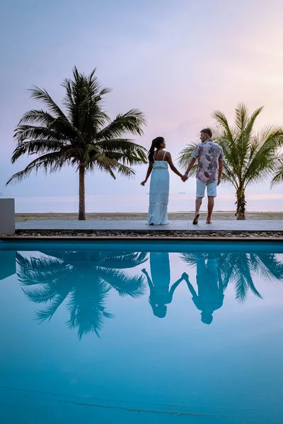 Couple men and woman during sunrise by the swimming pool looking out over the beach of Chumphon Thailand — Stok fotoğraf