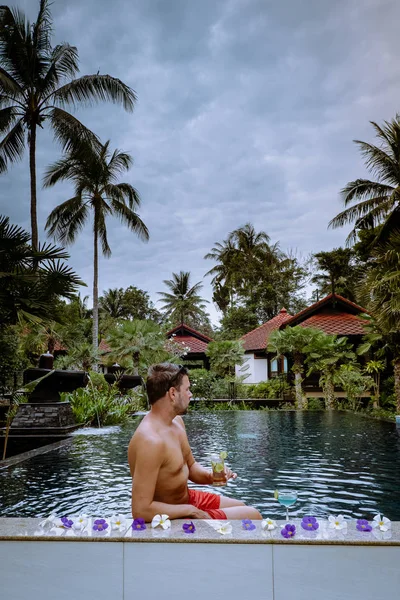 Guy drinking cocktails by the pool during vacation in Thailand — ストック写真