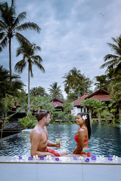 Casal bebendo coquetéis na piscina durante as férias na Tailândia — Fotografia de Stock