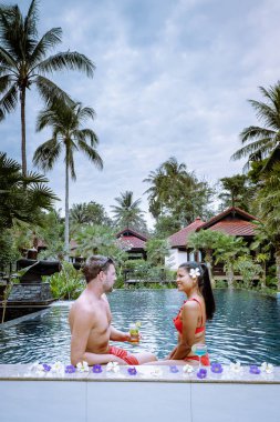 Tayland 'da tatilde havuz kenarında kokteyl içen çift.
