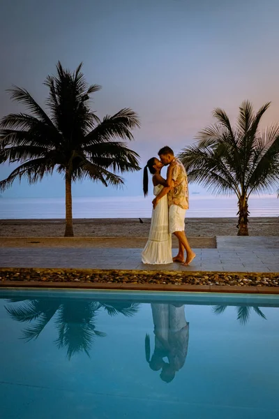 Casal homens e mulheres durante o nascer do sol junto à piscina com vista para a praia de Chumphon Tailândia — Fotografia de Stock