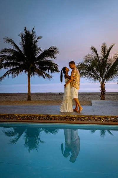 Пара мужчин и женщин во время восхода солнца у бассейна, глядя на пляж Chumphon Таиланд — стоковое фото