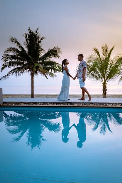 Casal homens e mulheres durante o nascer do sol junto à piscina com vista para a praia de Chumphon Tailândia — Fotografia de Stock