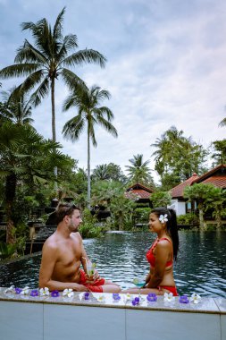 Tayland 'da tatilde havuz kenarında kokteyl içen çift.