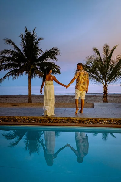 Casal homens e mulheres durante o nascer do sol junto à piscina com vista para a praia de Chumphon Tailândia — Fotografia de Stock