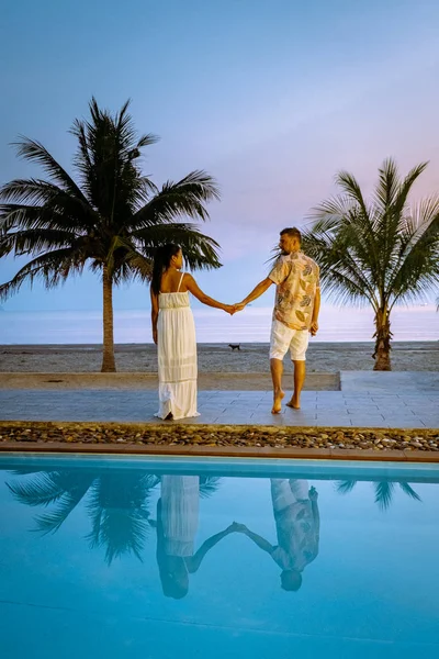 Couple men and woman during sunrise by the swimming pool looking out over the beach of Chumphon Thailand — 스톡 사진