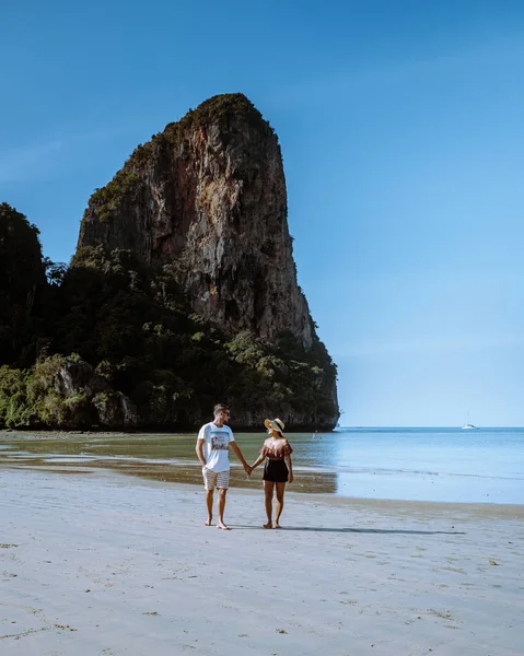 Railay Beach Krabi Thailand, couple walking in the morning on the beach with tropical cliffs and long tail boats on the background at the Island of Railay beach Krabi — ストック写真