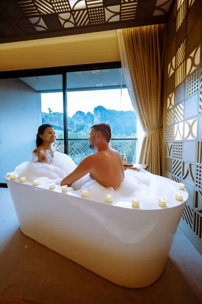 Pareja en baño viendo la puesta de sol en la bañera en el baño durante las vacaciones en Tailandia viendo la puesta de sol sobre el océano y las tuberías — Foto de Stock