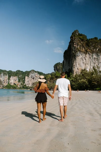 Railay Beach Krabi Thailandia, coppia che cammina al mattino sulla spiaggia con scogliere tropicali e lunghe barche a coda sullo sfondo presso l'Isola di Railay spiaggia Krabi — Foto Stock