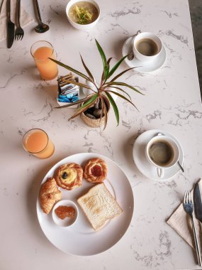 Kahvaltı masasının üst görüntüsü, yumurta, kruvasan, kahve, portakal suyu.