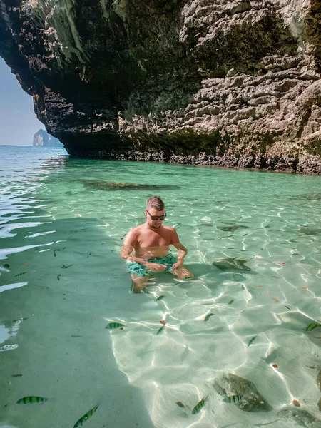 Guy in swim short on the beach of Koh poda Island Krabi Thailand, men in yellow short on the beach on a bright sunny day with blue sky