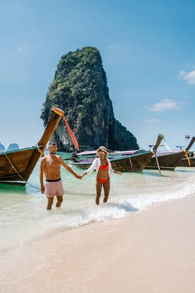 Railay Beach Krabi Tailandia, pareja caminando por la mañana en la playa con acantilados tropicales y barcos de cola larga en el fondo en la isla de Railay playa Krabi — Foto de Stock